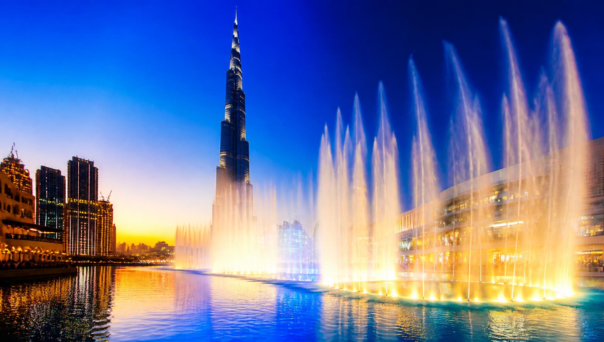 Dubai Fountain show at twilight with Burj Khalifa and colourful lights